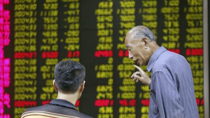 Investors talk in front of an electronic board showing stock information at a brokerage house in Beijing