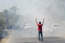 An anti-government protester gestures as he stands in tear gas fired by riot police as he tries to walk towards Diraz