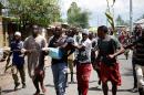 Burundian protesters carry a man injured in clashes with police in the Buterere area of the capital Bujumbura, on May 12, 2015