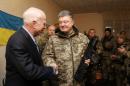 Ukrainian President Poroshenko shakes hands with U.S. Senator McCain during a meeting with Ukrainian servicemen in Shirokino settlement near Mariupol