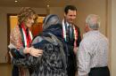 This photo taken on March 20, 2014, posted on the official Facebook page of the Syrian Presidency, shows first lady Asma Assad, left background, and Syrian President Bashar Assad, right background, shaking hands with Syrian teachers in Damascus, Syria. As Syrian army made gains on the battlefield, Assad's Britain-born wife has come out of seclusion, joining her husband's campaign to infuse confidence and optimism into the war-wrecked nation. Since January, Asma Assad has made several carefully scripted public appearances in the past months. (AP Photo/Syrian Presidency via Facebook)