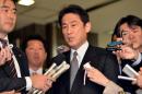 Japanese Foreign Minister Fumio Kishida (C) is surrounded by reporters in Tokyo on December 20, 2013