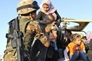 A Jordanian soldier helps Syrian refugees fleeing violence in their country after they crossed the border into Jordanian territory with their families from Syria into Jordan, near the town of Ramtha