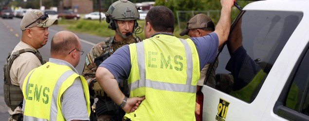 Law enforcement officials speak to EMS technicians outside a bank during what police say is a hostage situation in St. Joseph, La. (Rogelio V. Solis/AP)