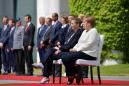Merkel sits during anthems after shaking spells